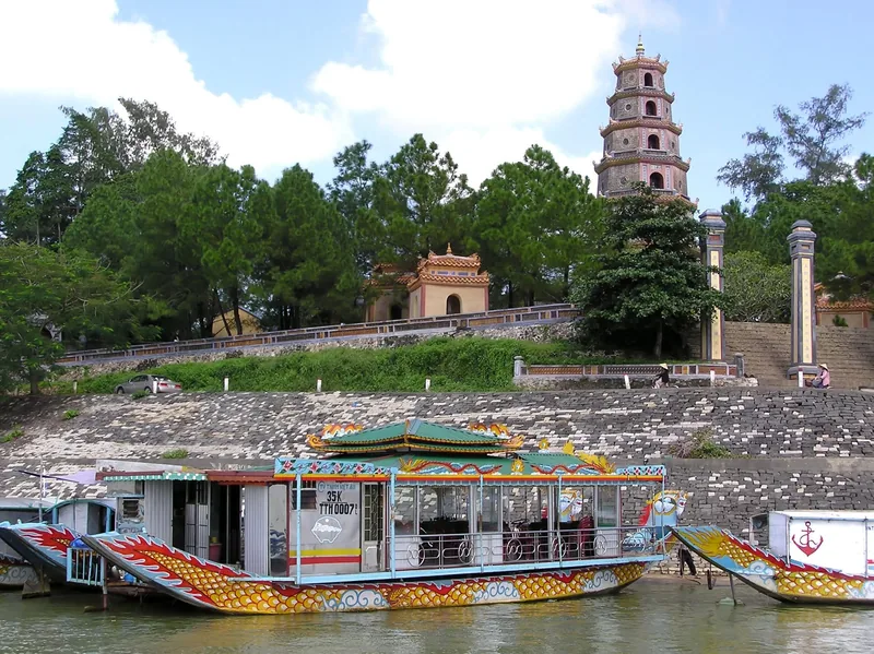 A dragon boat floats on the Perfume River below Thien Mu Pagoda's seven-tiered tower in Hue.
