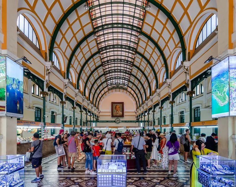 Visitors browse souvenir stalls beneath the arched glass ceiling of Ho Chi Minh City's Central Post Office.